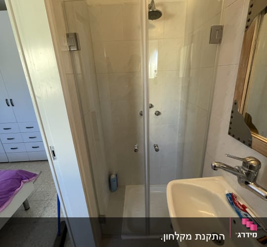 מקלחון זכוכית עם ראש מקלחת ובקבוק סבון